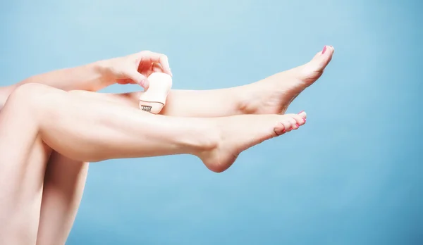 Kadın tıraş makinesi tüy dökücü vücut bakımıyla bacağını tıraş ediyor. — Stok fotoğraf