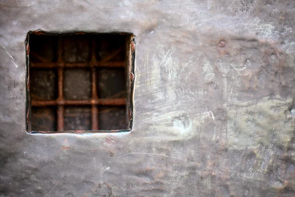 Cell window with stell lattice in gray metal wall — Stock Photo, Image