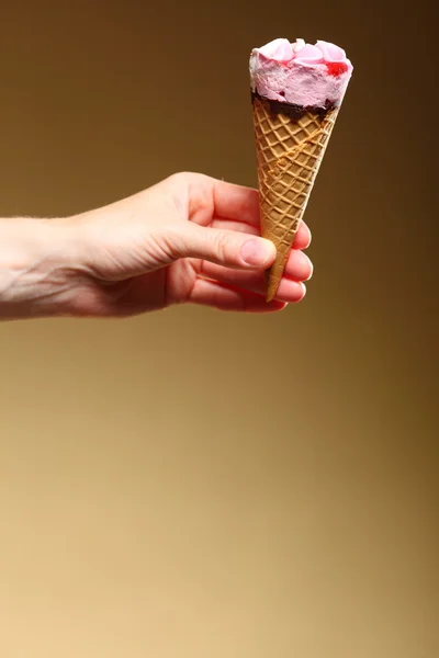 Berry icecream cone in hand on brown — Stock Photo, Image