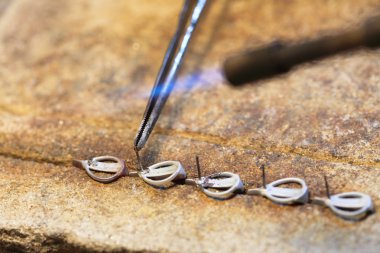 Cloceup jeweller at work silver soldering clipart