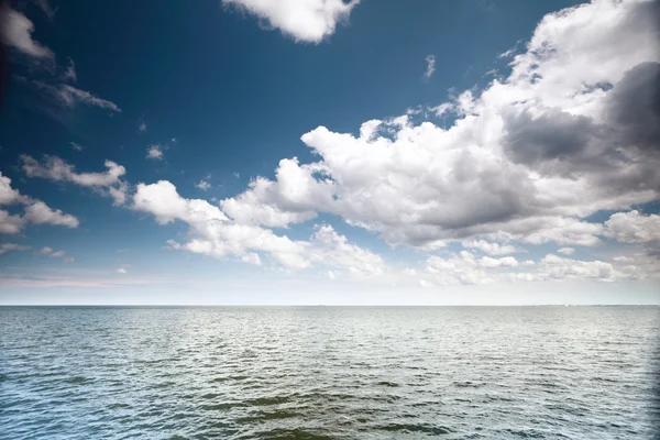 Bewolkt blauwe lucht boven een zeeoppervlak — Stockfoto