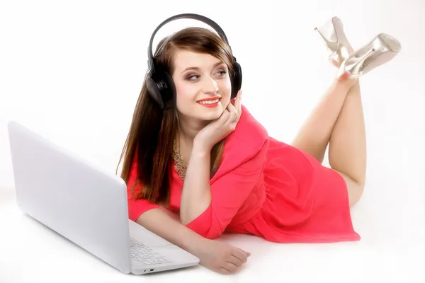 Menina bonito com fones de ouvido e laptop deitado — Fotografia de Stock