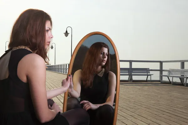 Thoughtful woman looks at the reflection in mirror — Stock Photo, Image