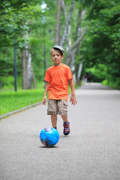 Мальчик пинает мяч на улице. — стоковое фото