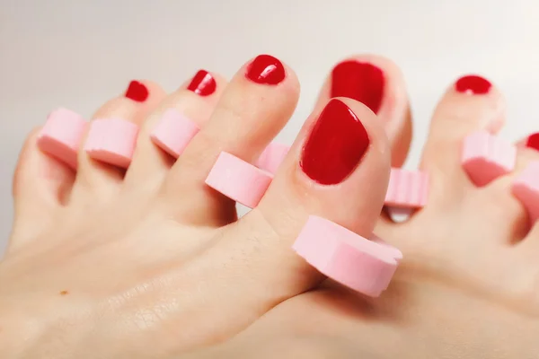 Pedicura del pie aplicando uñas de los pies rojas — Foto de Stock