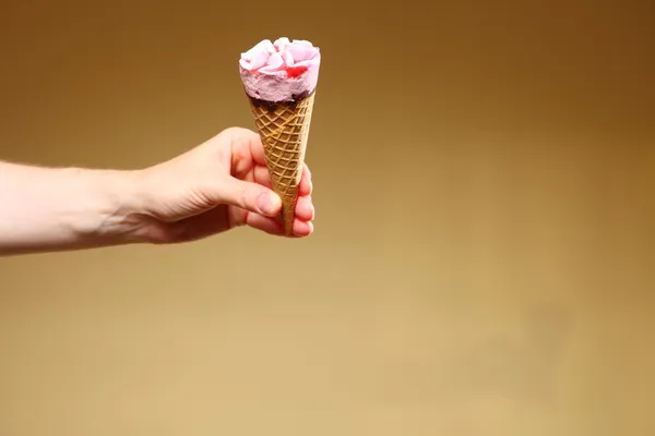 Berry icecream cone in hand on brown — Stock Photo, Image