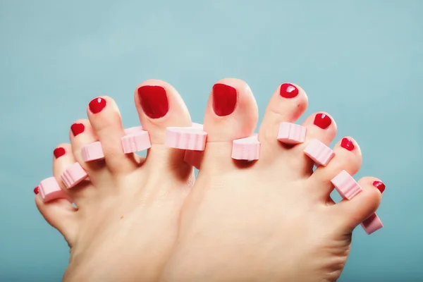 Foot pedicure applying red toenails on blue — Stock Photo, Image