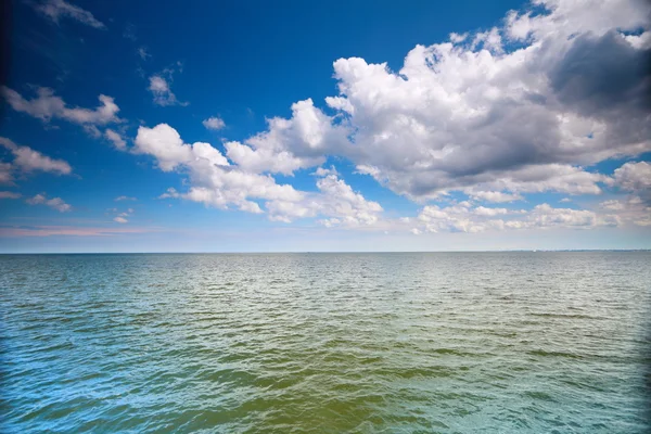 Облачно-голубое небо над поверхностью моря — стоковое фото