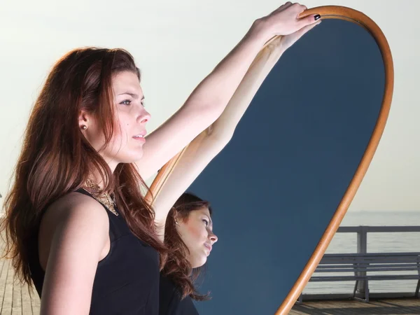 Doordachte vrouw kijkt naar de reflectie in de spiegel — Stockfoto