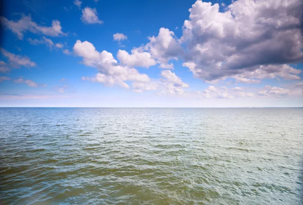 Bewölkter blauer Himmel über einer Meeresoberfläche — Stockfoto