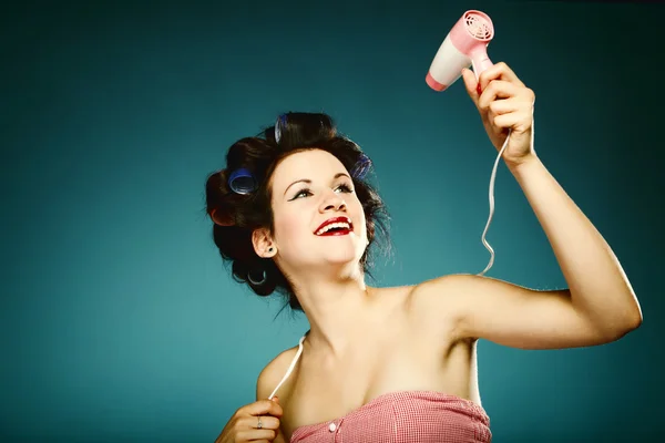 Funny girl in curlers with hairdryer styling hair — Stock Photo, Image