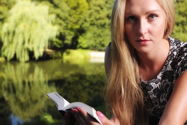 Блондинка с книгой на зеленом фоне городского парка — стоковое фото
