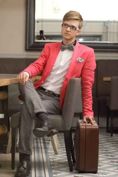 Młody przystojny stylowy mężczyzna z walizką czeka — Zdjęcie stockowe