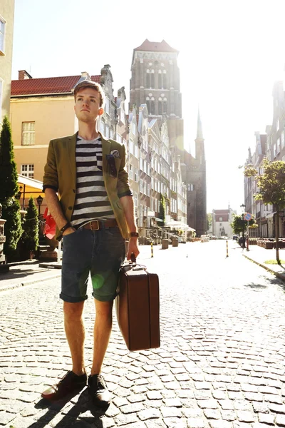 Young handsome man with suitcase on street — Stock Photo, Image