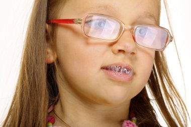 Close up little girl in glasses doing fun saliva bubbles clipart