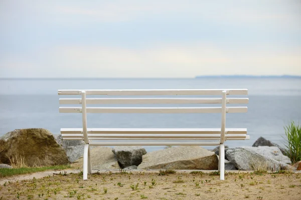 Белая деревянная скамейка на берегу моря — стоковое фото