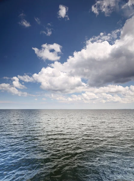Cloudy blue sky above a surface of the sea Stock Photo