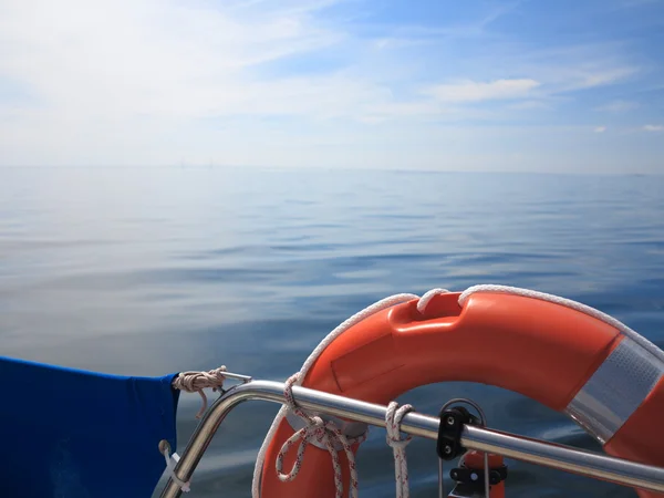 Rescue red lifebuoy on sail and blue sky sea — Stock Photo, Image