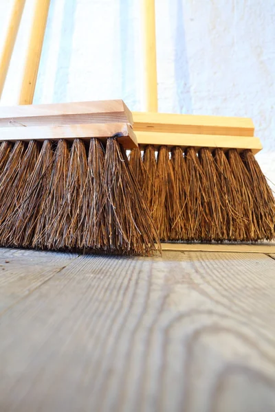 Escobas grandes en las tareas domésticas piso de madera — Foto de Stock