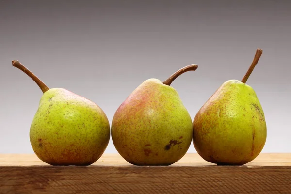Τρεις αχλάδια φρούτα στο ξύλινο τραπέζι — Φωτογραφία Αρχείου