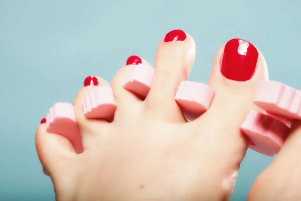 Pedicure del piede applicando unghie rosse su blu — Foto Stock