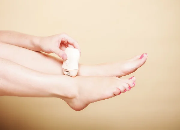 Kadın tıraş makinesi tüy dökücü vücut bakımıyla bacağını tıraş ediyor. — Stok fotoğraf