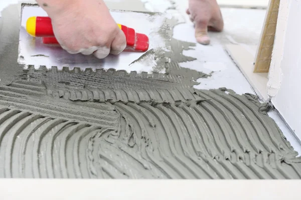 Trabalhador da construção é azulejos em casa, adesivo piso de azulejo — Fotografia de Stock