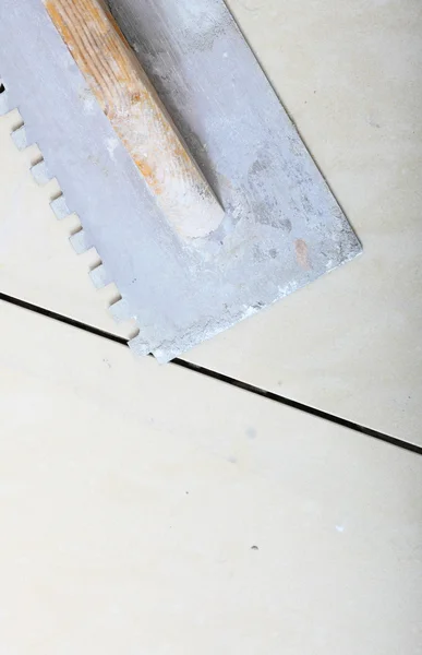 Building work tool dirty trowel on new tile floor surface — Stock Photo, Image