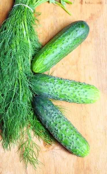 Bund frischer Dill und Gurken auf Holztisch — Stockfoto