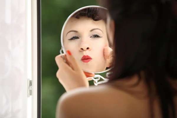 Chica retro estilo aplicación maquillaje mirando espejo interior — Foto de Stock
