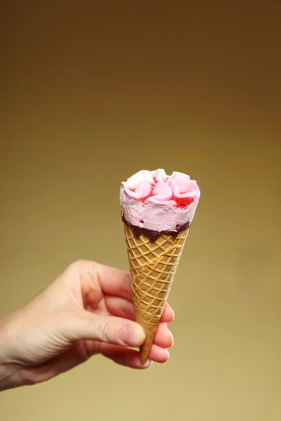 Berry icecream cone in hand on brown — Stock Photo, Image