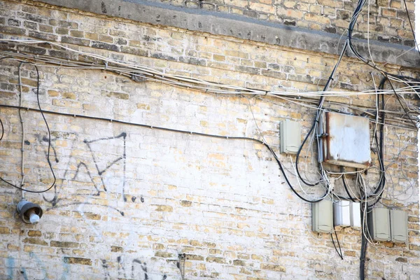 Электроконтроллер и клубок кабелей на кирпичной стене — стоковое фото