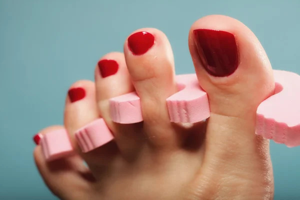 Nožní pedikúra nanášení červených nehtů na modré — Stock fotografie