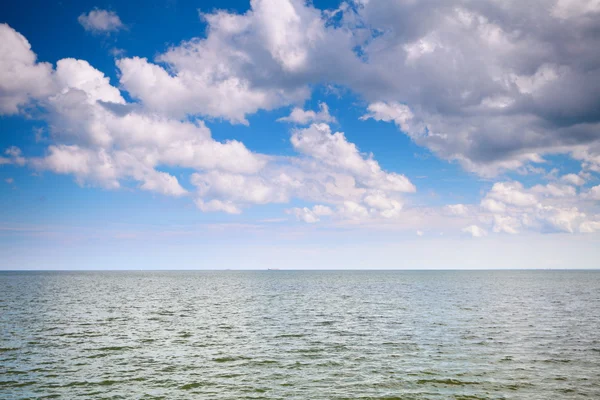 Bewölkter blauer Himmel über einer Meeresoberfläche — Stockfoto