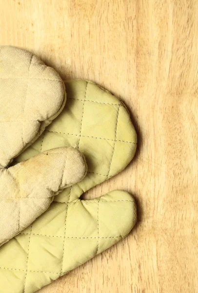 Old wooden kitchen board with protective oven glove — Stock Photo, Image