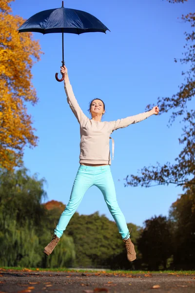 Söt flicka hoppa med paraply i höstlig park — Stockfoto