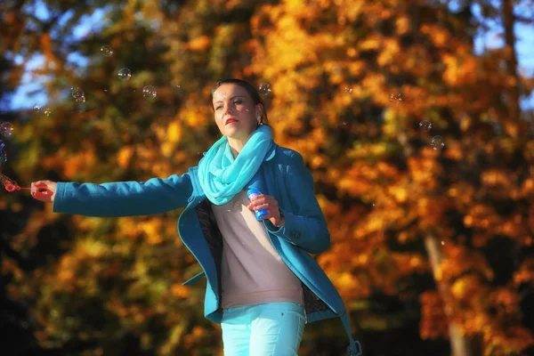 Donna che si diverte soffiando bolle nel parco autunnale — Foto Stock