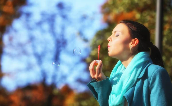 Woman having fun blowing bubbles in autumnal park — Stock Photo, Image