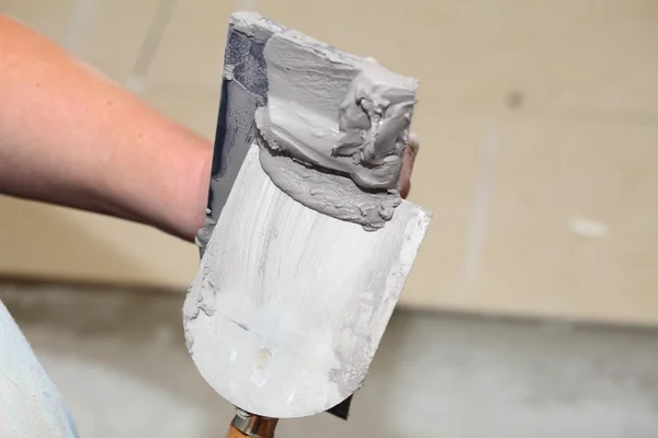 Ręka trzyma wiaderko kielnia z zaprawy cementowej — Zdjęcie stockowe