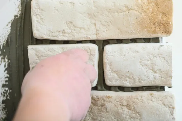 Trabajador de la construcción la instalación de azulejos en una pared — Foto de Stock