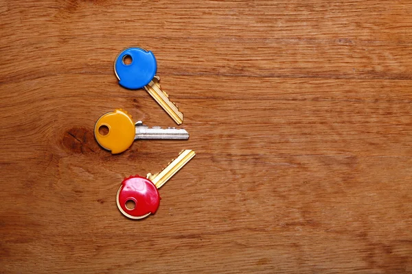 House keys with colorful plastic coats caps on table — Stock Photo, Image