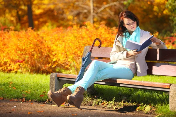 Ung flicka avkopplande i höstlig park läsa bok — Stockfoto