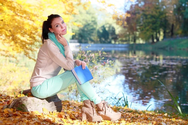 Jong meisje ontspannen in herfst park leesboek — Stockfoto