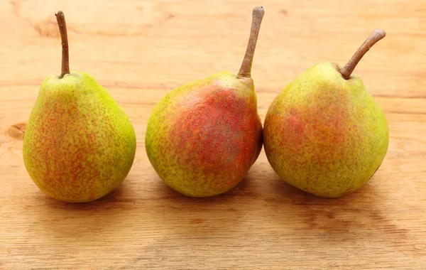Τρεις αχλάδια φρούτα σε ξύλινο τραπέζι φόντο — Φωτογραφία Αρχείου