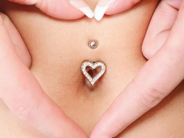 Mains coeur symbole autour de piercing nombril — Photo