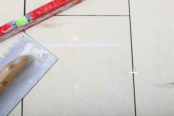 Εργασία εργαλείο οικοδόμησης οδοντωτό μυστρί επίπεδο στην επιφάνεια του δαπέδου κεραμιδιών — Φωτογραφία Αρχείου