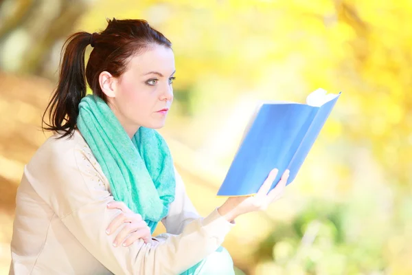 Junges Mädchen entspannt sich im herbstlichen Park beim Lesen von Buch — Stockfoto