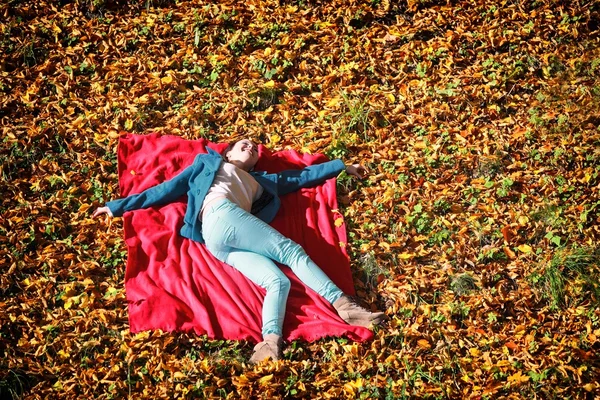 赤い毛布の上に横たわる秋の公園でリラックス若い女の子 — ストック写真