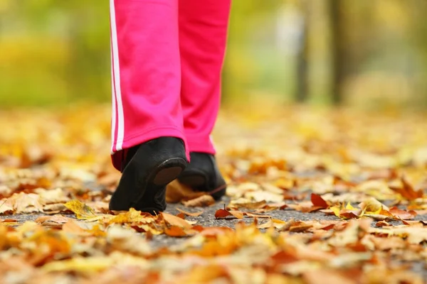 ランナーの足のランニング シューズ。秋の公園でジョギングの女性 — ストック写真
