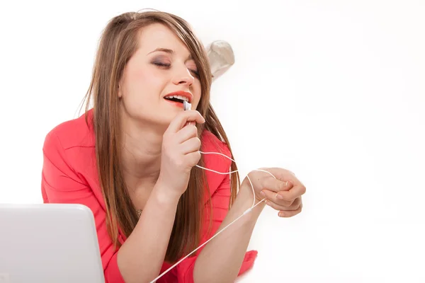 Leuk meisje met hoofdtelefoons en laptop liegen geïsoleerde — Stockfoto